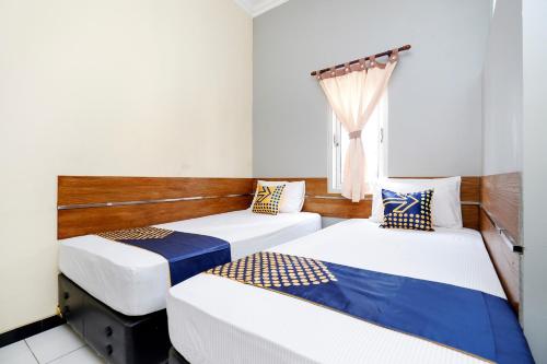 two beds in a room with a window at Hotel O Solo Point Guest House Syariah in Solo