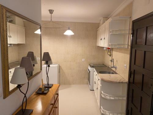 eine kleine Küche mit weißen Schränken und einem Waschbecken in der Unterkunft Casa Mouzinho de Albuquerque in Ourém