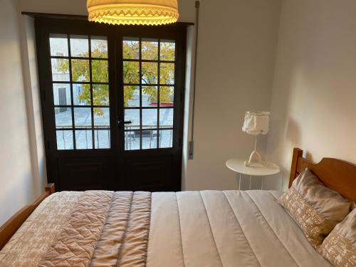 ein Schlafzimmer mit einem Bett und eine Tür mit einem Fenster in der Unterkunft Casa Mouzinho de Albuquerque in Ourém