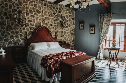 una camera da letto con un letto e un muro di pietra di Casa Rural Los Jarales Número Registro TR-CC-00365 a Casar de Cáceres