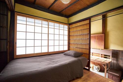 een slaapkamer met een bed in een kamer met ramen bij Koke-an in Kyoto