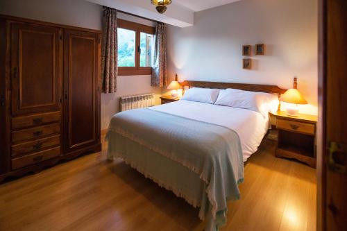 a bedroom with a large bed and two lamps on tables at Foratata - con piscina, familiar y muy acogedor in Sallent de Gállego