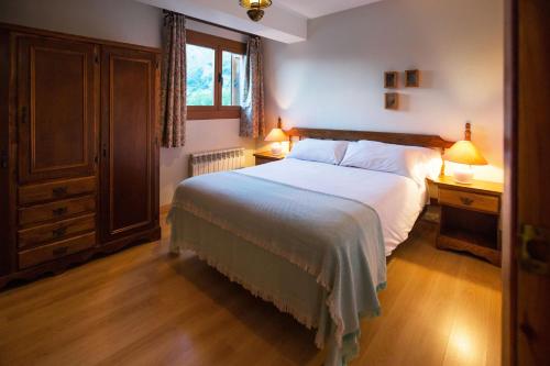 a bedroom with a large bed and two lamps on tables at Foratata - familiar y muy acogedor BY PIRINEOS 360 in Sallent de Gállego