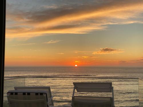 - deux chaises assises sur la plage au coucher du soleil dans l'établissement Balcony Beach Apartment • BBA • Moledo, à Moledo