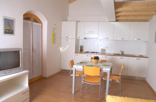 eine Küche mit einem Tisch und Stühlen sowie einem TV in der Unterkunft Windshouse in Nago-Torbole