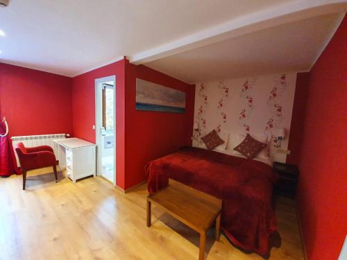 a bedroom with red walls and a bed and a table at Croix Blanche de Sologne in Chaumont-sur-Tharonne