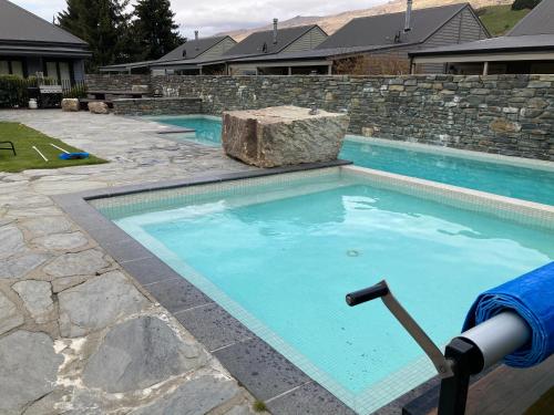 a swimming pool in a yard with a stone wall at Cardrona Valley Studio (17) in Cardrona