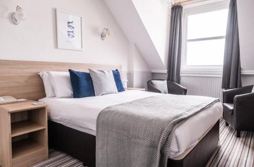 a bedroom with a bed with blue pillows and a window at The Elizabeth in Sidmouth
