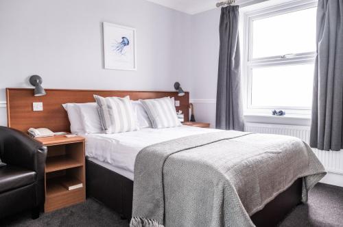 a bedroom with a bed and a chair and a window at The Elizabeth in Sidmouth