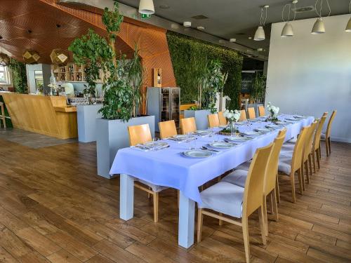 a long table in a restaurant with white tables and chairs at Antonińska Hotel & Apartamenty in Leszno