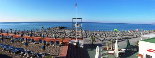 a group of chairs and umbrellas on a beach at Gold Hotel in Bordighera