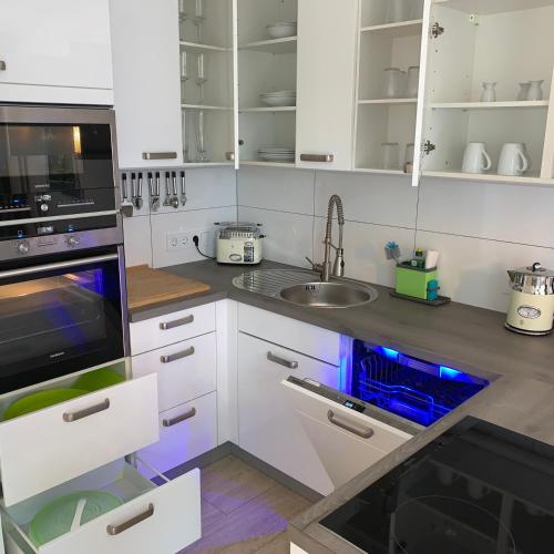 a kitchen with white cabinets and a sink with blue lights at Park-Lodge Am Rohrbusch in Münster
