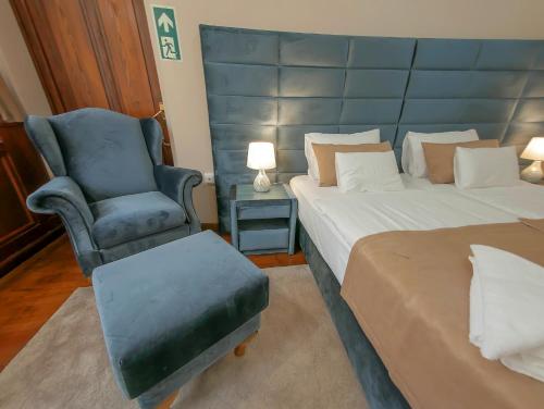 a bedroom with a large bed and a chair at Belga Boutique Panzió in Debrecen