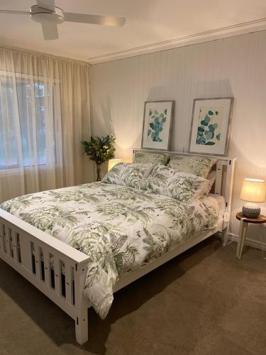a white bed in a bedroom with two pictures on the wall at Red Tail Retreat in Collie
