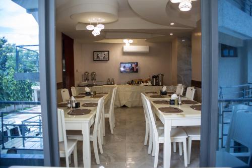 una sala da pranzo con tavoli bianchi e sedie bianche di Sunset Vista Hotel a Kigoma