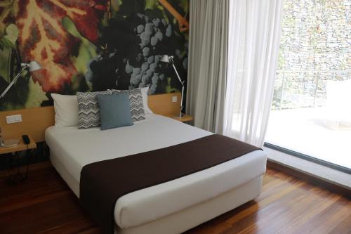 a bedroom with a bed with a painting on the wall at LBV House Hotel in Pinhão