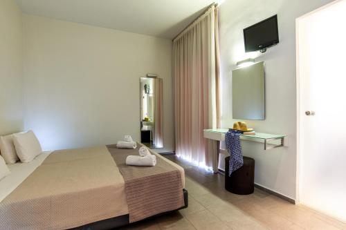 a bedroom with a bed and a desk and a television at Atlantis Boutique City Hotel in Rhodes Town