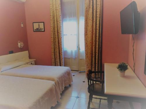 Habitación de hotel con 2 camas, mesa y ventana en Hostal Don Jaime I y II, en Segovia