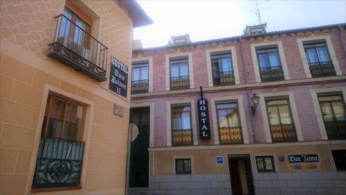 un gran edificio de ladrillo con ventanas y balcones. en Hostal Don Jaime I y II, en Segovia