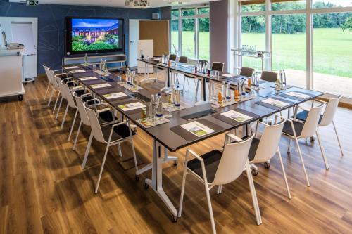 a conference room with tables and chairs and a tv at Hofgut Algertshausen in Eresing