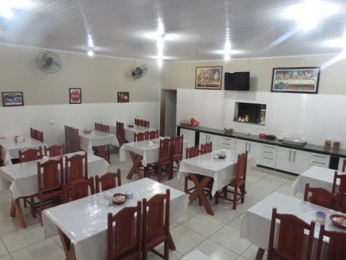 a restaurant with white tables and chairs and a television at Barbara's Hotel in Junqueirópolis
