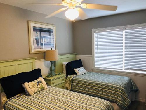 a bedroom with two beds and a ceiling fan at Amazing beach getaway pool condo by the beach in Bradenton Beach