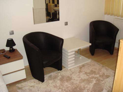 two black chairs sitting next to a white desk and a table at Brasch Apartman in Fertőrákos
