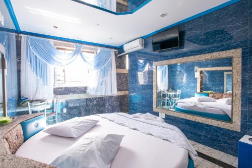 ein blaues Schlafzimmer mit einem Bett und einem Spiegel in der Unterkunft Motel Desejo in Porto Alegre