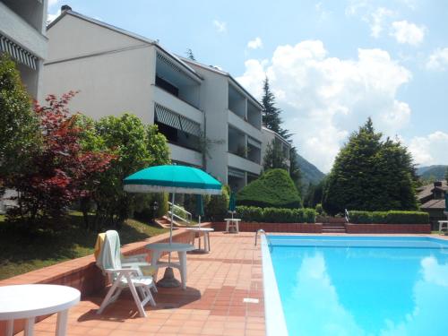 een zwembad met een tafel en stoelen en een parasol bij Valsassina Rent in Introbio