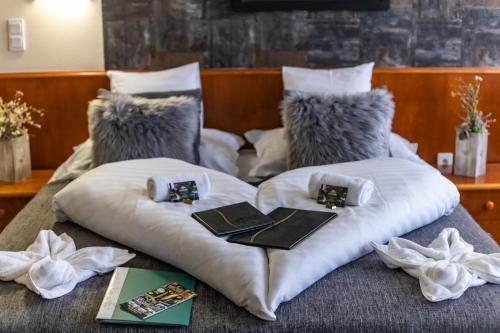 a bed with white pillows and books on it at 4 Évszak Hegyihotel in Mátraháza