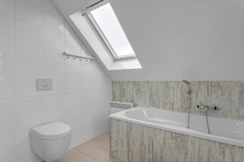 a bathroom with a bath tub and a skylight at Guesthouse Vatnsholt in Vatnsholt