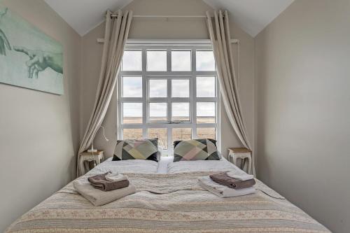 a bed in a bedroom with a large window at Guesthouse Vatnsholt in Vatnsholt