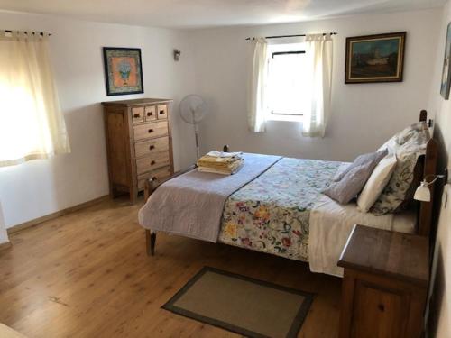 um quarto com uma cama, uma cómoda e uma janela em Typical small house near Lisbon em Oeiras