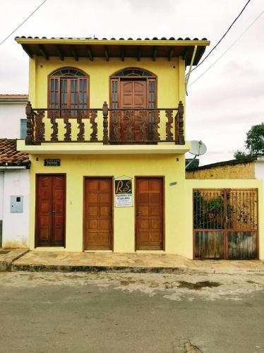 a yellow house with wooden doors and a balcony at Aconchego de Regina in Tiradentes