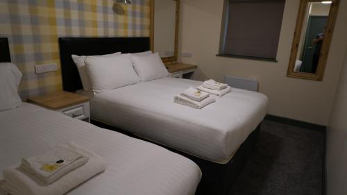 two beds in a hotel room with towels on them at Greenland's Inn in Longbridge