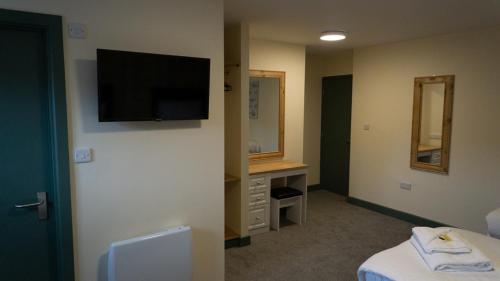 a hotel room with a television on a wall at Greenland's Inn in Longbridge