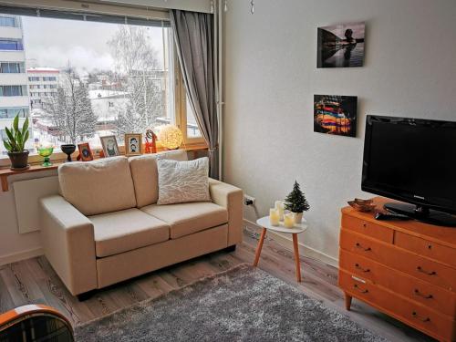 ein Wohnzimmer mit einem Sofa, einem TV und einem Fenster in der Unterkunft Torni-Mänttä in Mänttä