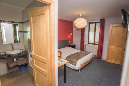 een slaapkamer met een bed en een badkamer met een wastafel bij Auberge le Sabot de Vénus in Méaudre