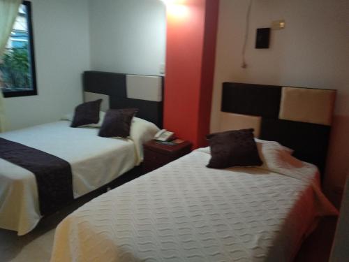 a hotel room with two beds and a red wall at Hotel Nova Park in Arauca