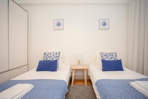 two beds in a small room with blue pillows at Liiiving in Porto | Light Spacious Apartment in Porto