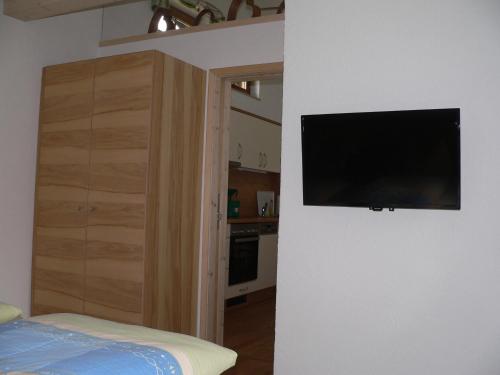 a bedroom with a flat screen tv on a wall at Gästehaus Gaisalpe in Fischen