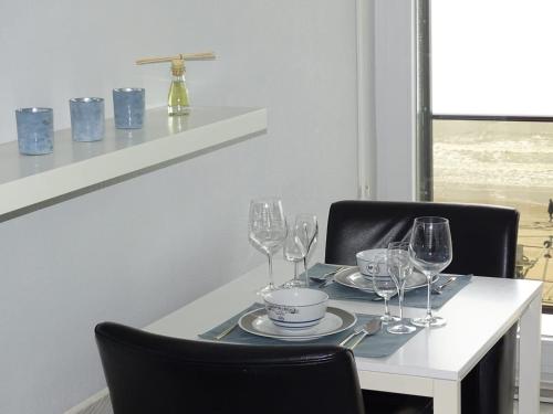 una mesa con copas de vino y platos en ella en Renovated studio direct Seaview en Ostende