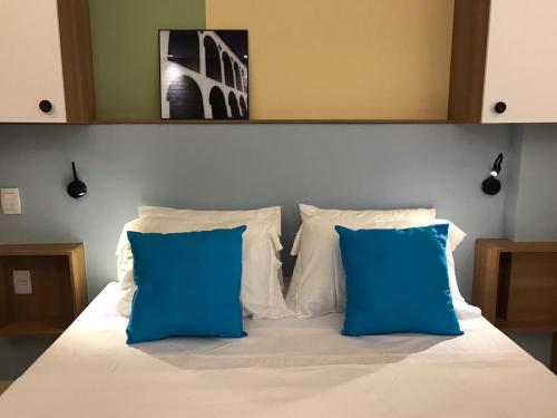 a bed with two blue pillows on top of it at Studio Praia Copacabana Beach in Rio de Janeiro