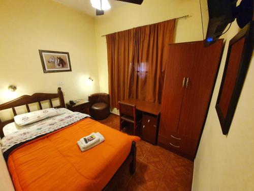 a bedroom with a bed with an orange blanket and a cabinet at Hotel Paris in San Martín