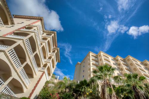 a building with palm trees in front of a blue sky at Princess Heights Luxury Condo Hotel in Dawn Beach