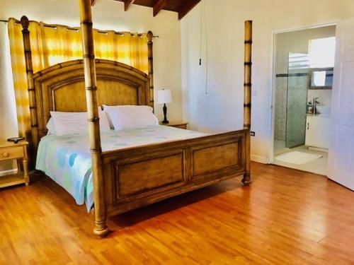 um quarto com uma cama de dossel e piso em madeira em Coral Villa em Saint Philip