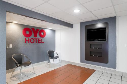 OYO Hotel Houston Katy Freeway في هيوستن: غرفة في الفندق مع كرسيين وتلفزيون على الحائط