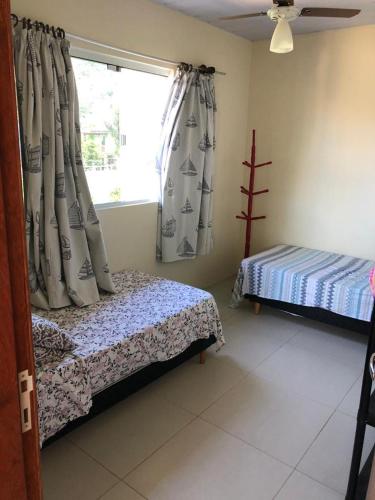 a bedroom with a bed and a window with curtains at Moradas Cantinho da Guarda in Guarda do Embaú