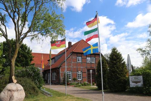 um edifício de tijolos vermelhos com bandeiras à frente em Mühlengasthof Landesbergen em Landesbergen