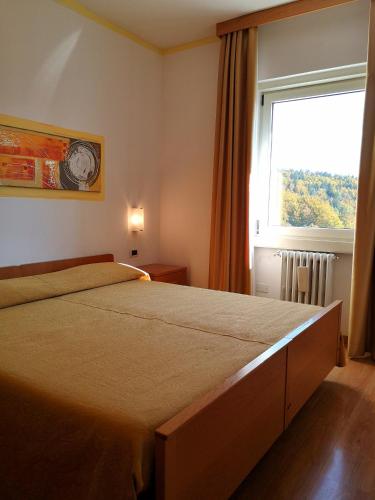 a bedroom with a large bed and a window at Residence Capriolo in Lavarone